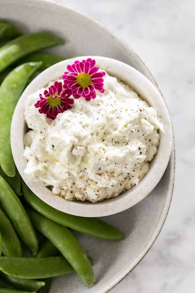 Blue cheese dip in a bowl with a side of snap peas. 