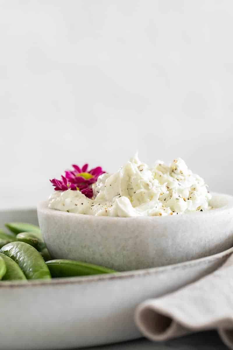 Blue cheese dip in a marble bowl garnished with flowers. 