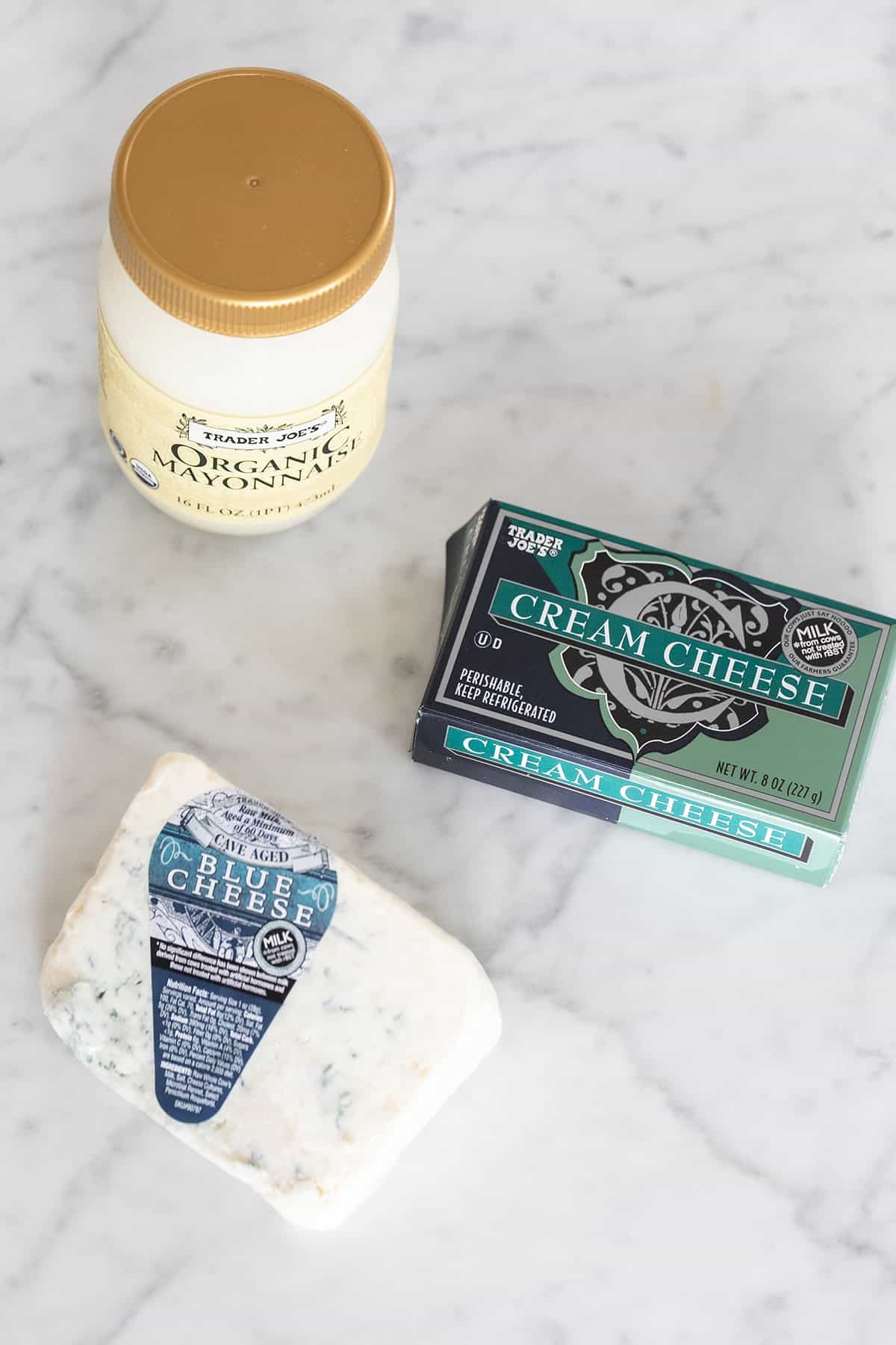 Three ingredients on a table to make blue cheese dip, Mayonaise, cream cheese and blue cheese.