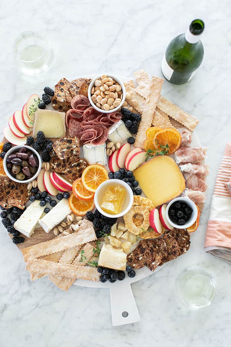 Large meat and cheese platter filled with cheese, berries, slices of fruit, and crackers. Perfect for a party.