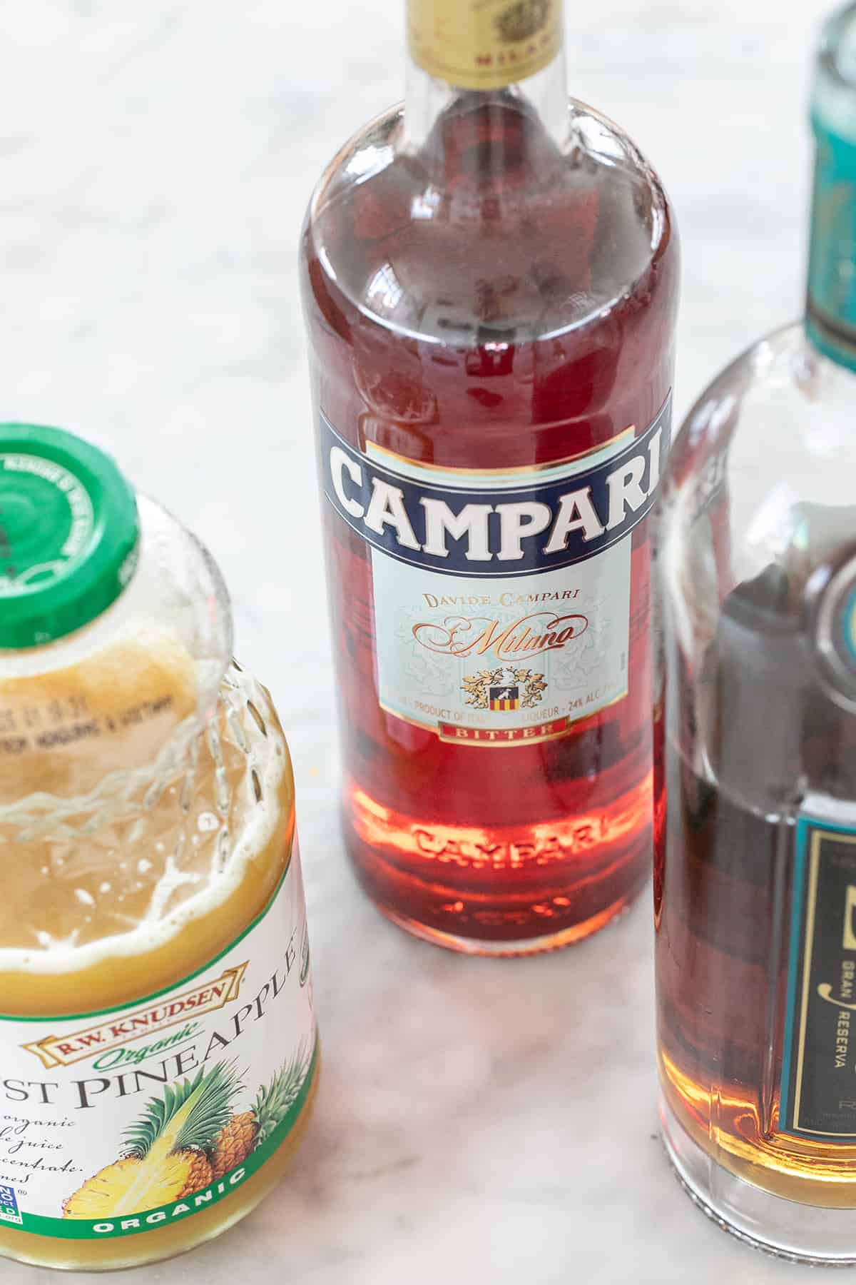 bottle of Campari, pineapple juice and dark rum