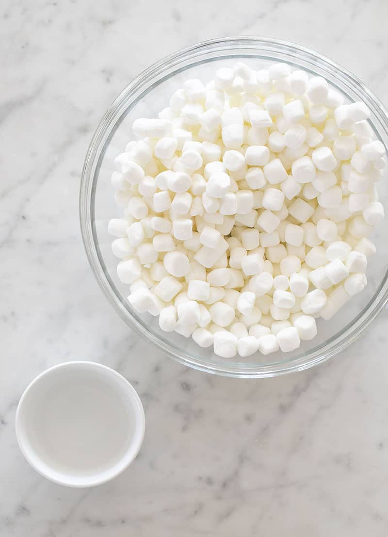 Mini marshmallows in a bowl with a small bowl of water.