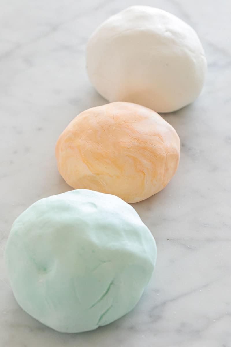 Three balls of colored marshmallow fondant in a row. 