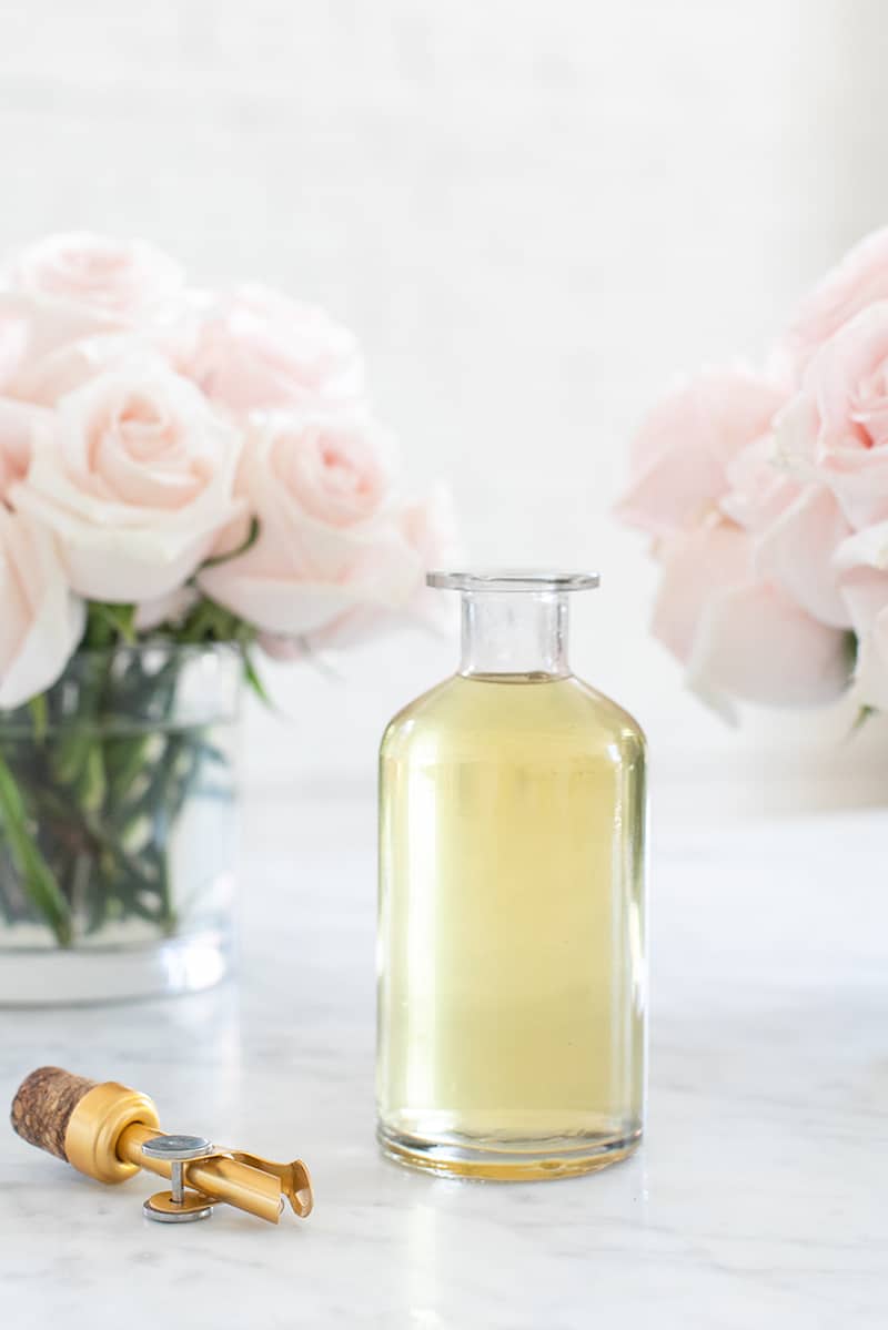 Bottle of rose water in a glass with a gold spout- nut milk bag