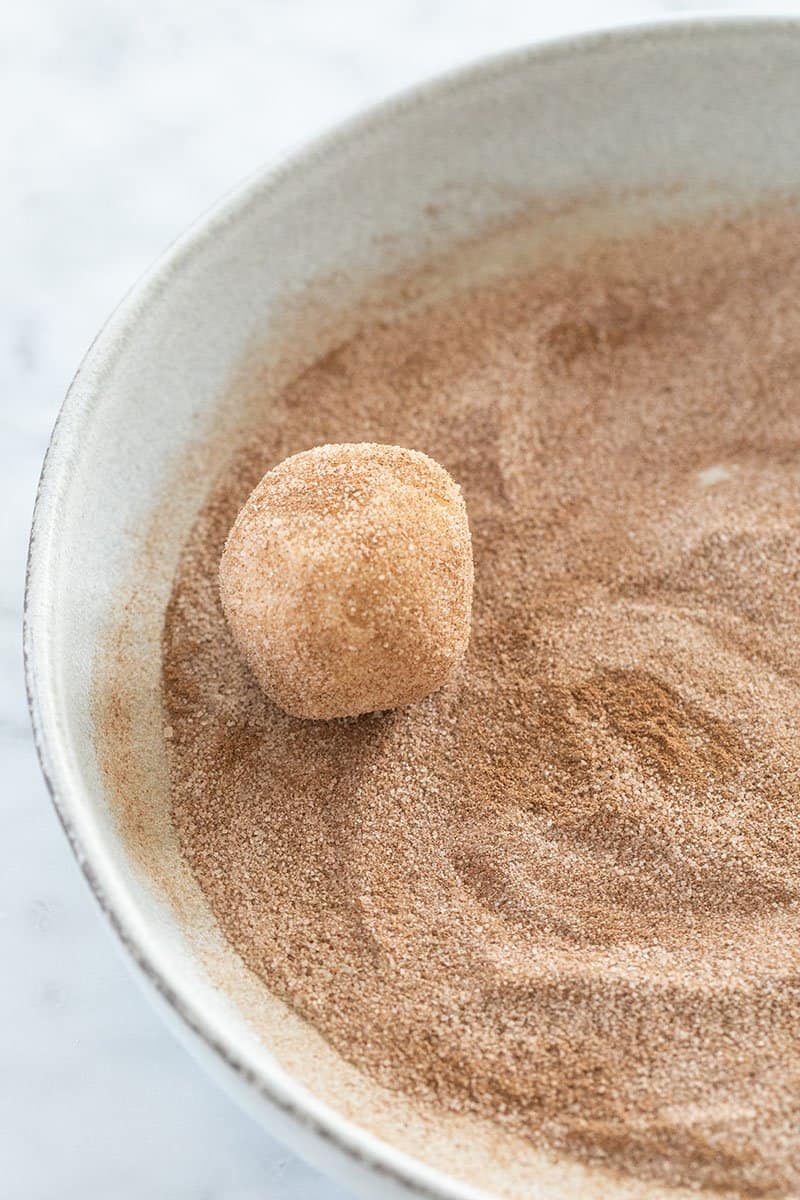 Rolling a snickerdoodle cookie into cinnamon and sugar.