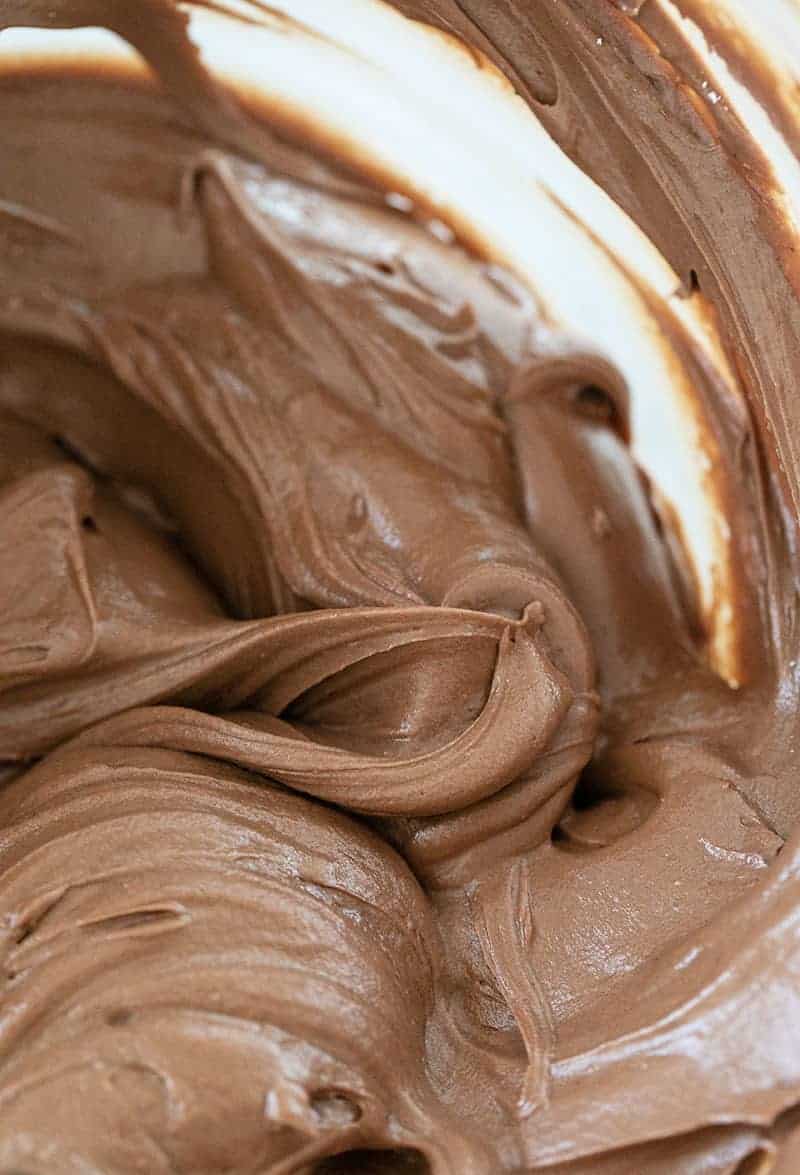 Chocolate buttercream frosting whipped in a mixing bowl.
