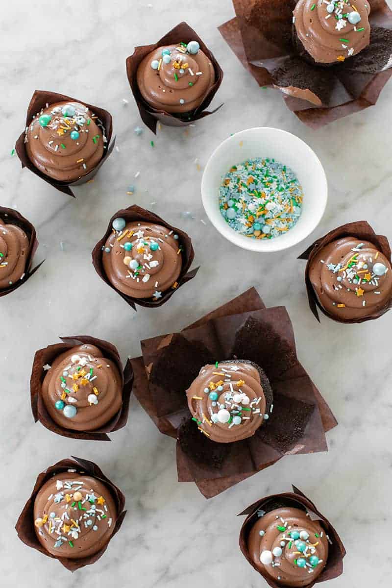 Chocolate cupcakes on a marble table with blue and gold sprinkles.