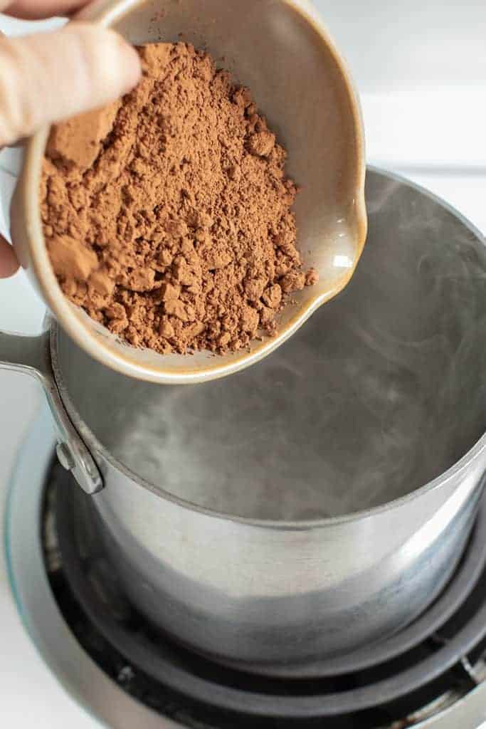 Adding cocoa powder into a metal pot.