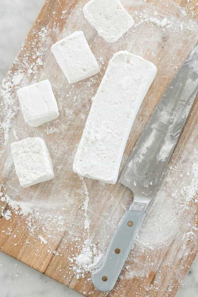 Cutting fluffy marshmallows on a cutting board.