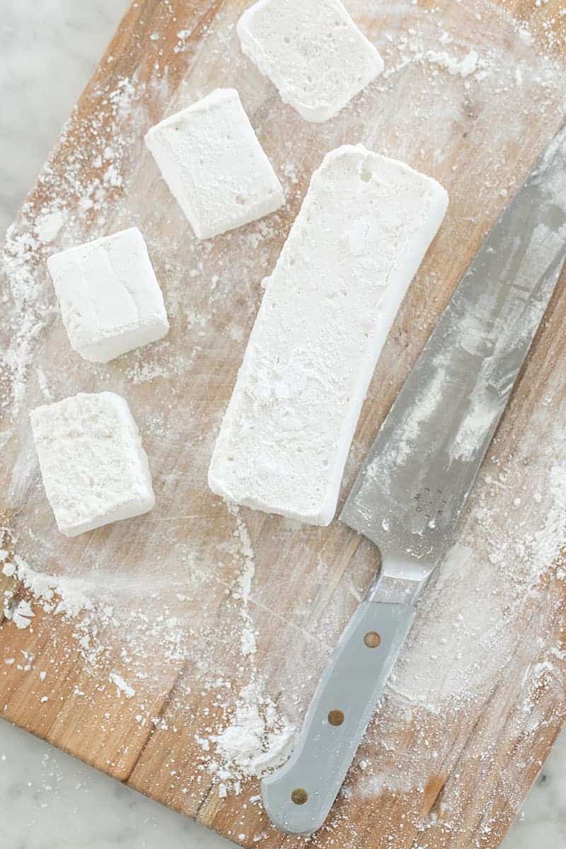 Cutting homemade marshmallows on a cutting board.