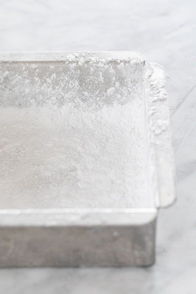 Preparing a pan with powdered sugar to make marshmallows.