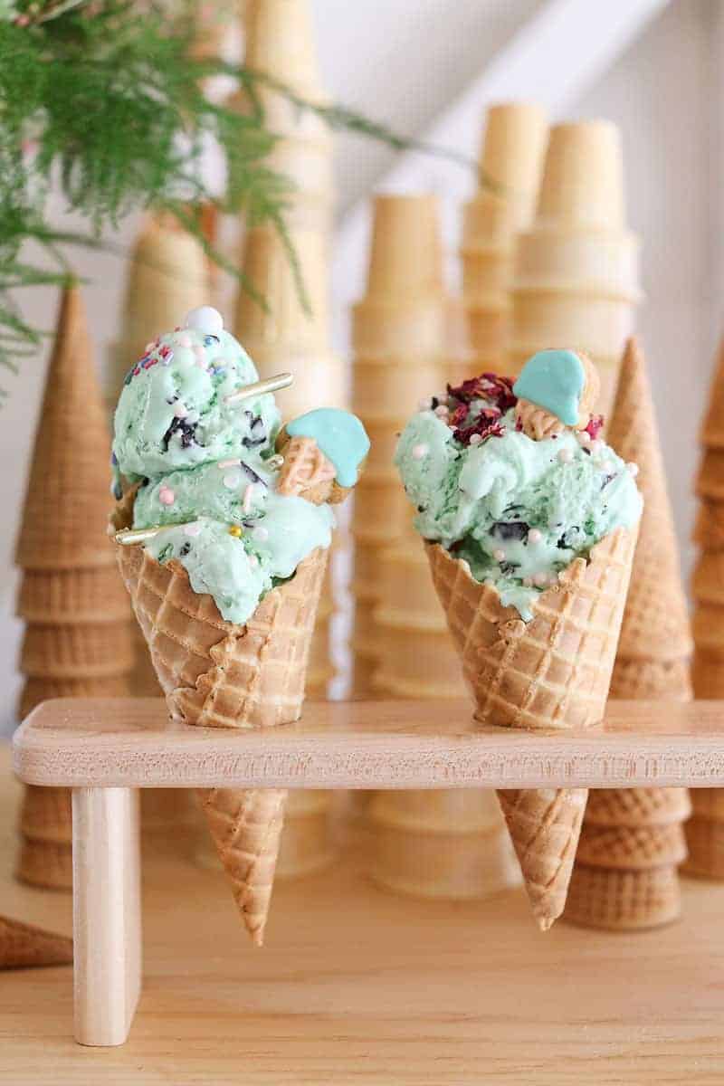 Ice cream in an ice cream holder with sprinkles in waffle cones. 