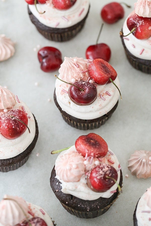 Cherry cupcakes with cherries, sprinkles on marble table.