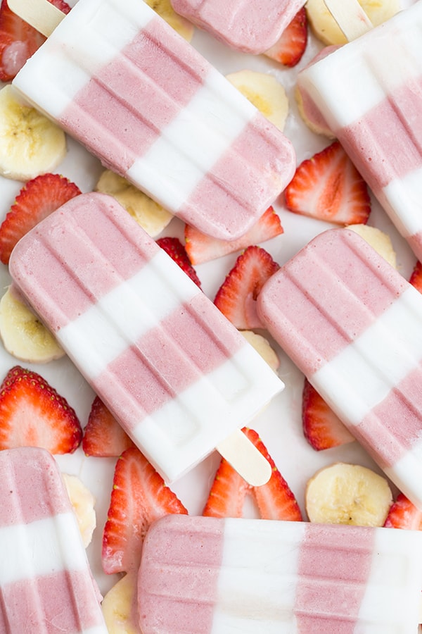 Strawberry and banana popsicles striped on sliced strawberries and bananas. 