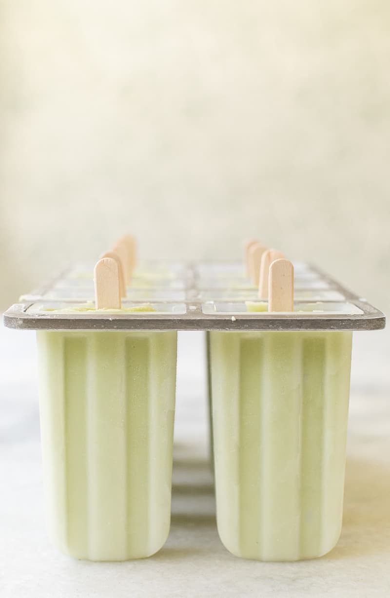 Green homemade popsicles in a popsicle mold. 