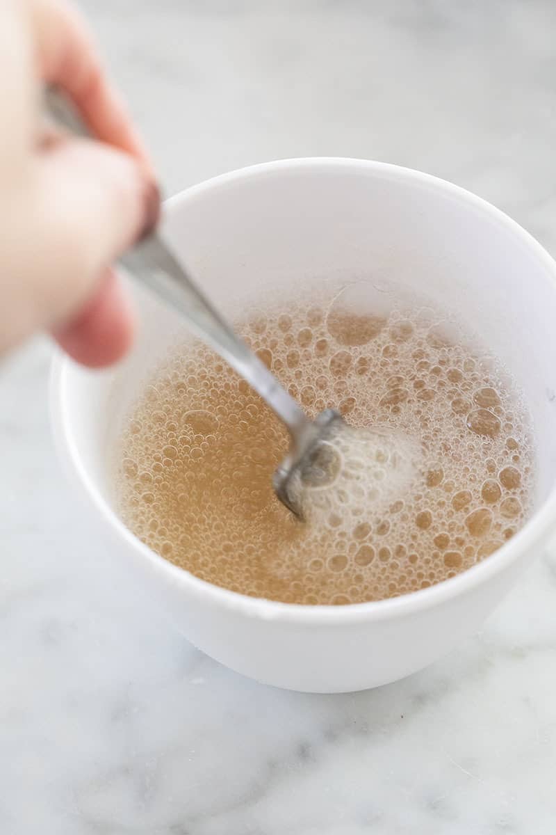 Whisking gelatin and water together in a small white bowl.