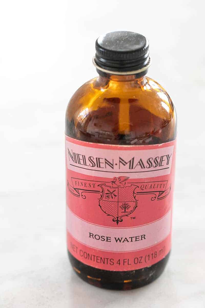 Rose water extract in a brown jar with a pink label. 