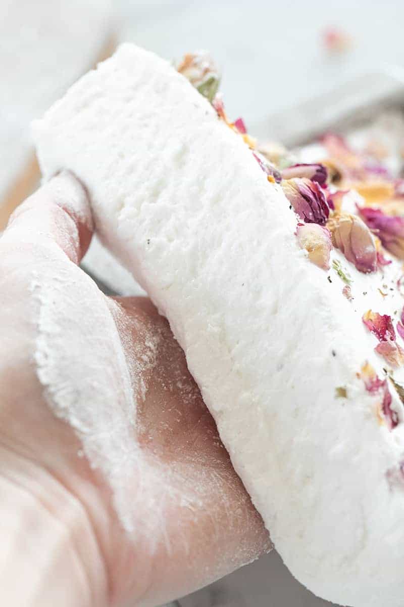 Hand pulling a marshmallow sheet out of a baking pan. 