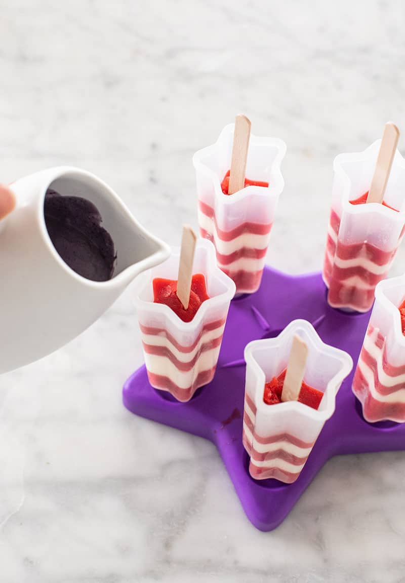 Pouring purple popsicle mold into a striped popsicle. 