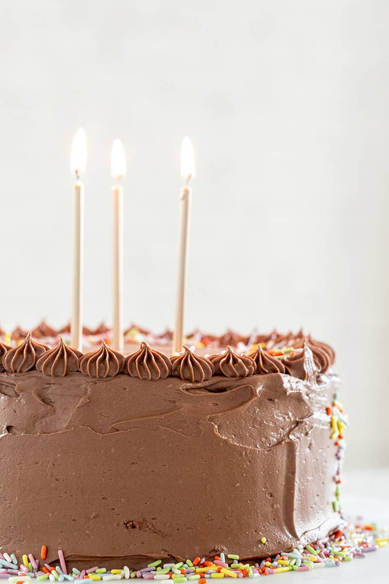 Birthday cake with candles and chocolate frosting with gold candles. 