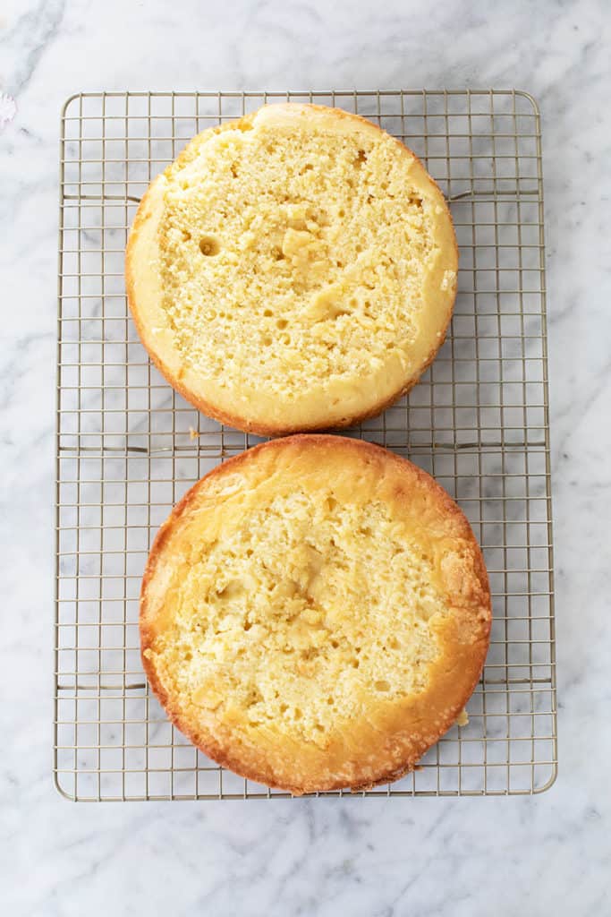 Two round birthday cakes on a cooling rack. 