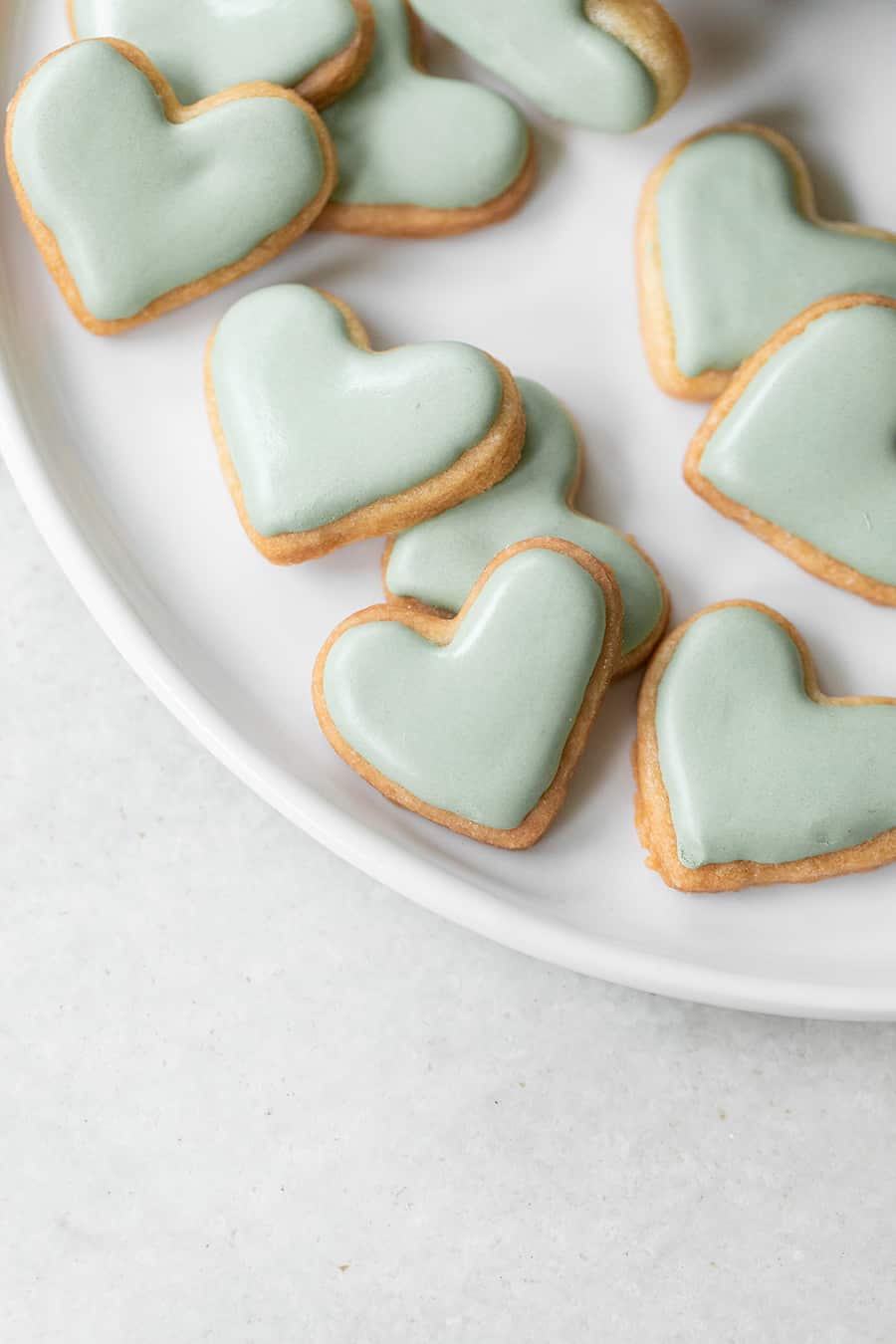 Small heart shaped cookies with green royal icing. 