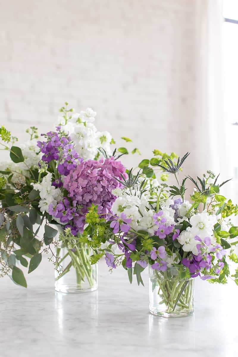 Purple and white flowers in old candle jars.