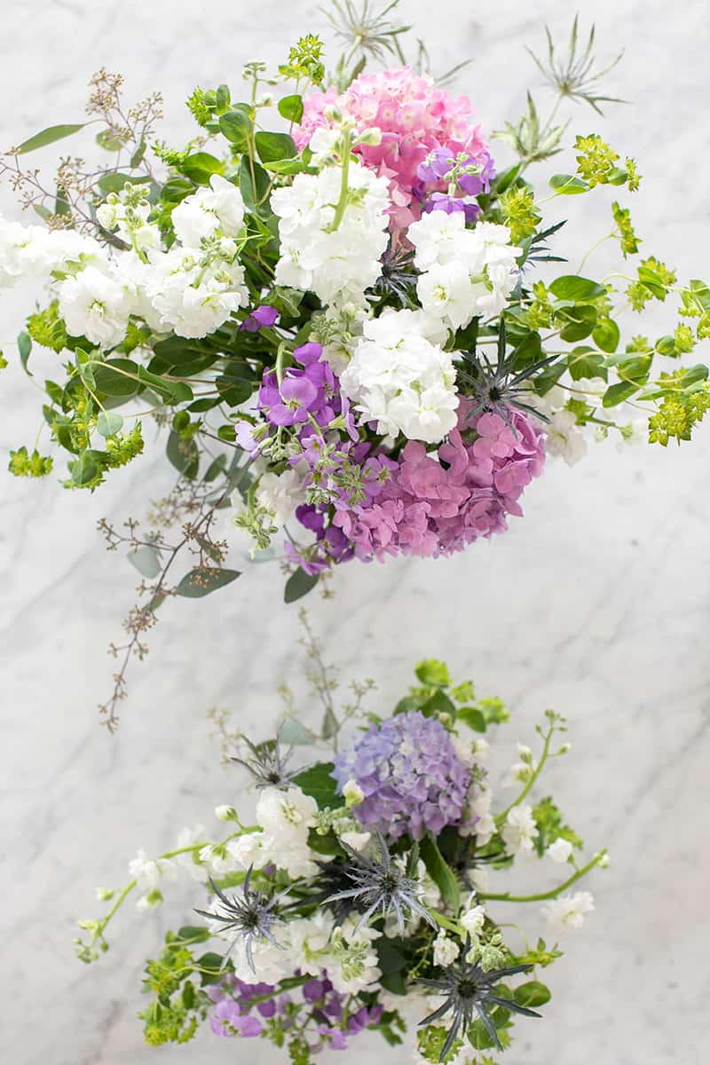 Purple and white flower arrangements  on a table.