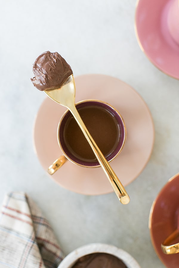 Spoon with chocolate over a shot of espresso.