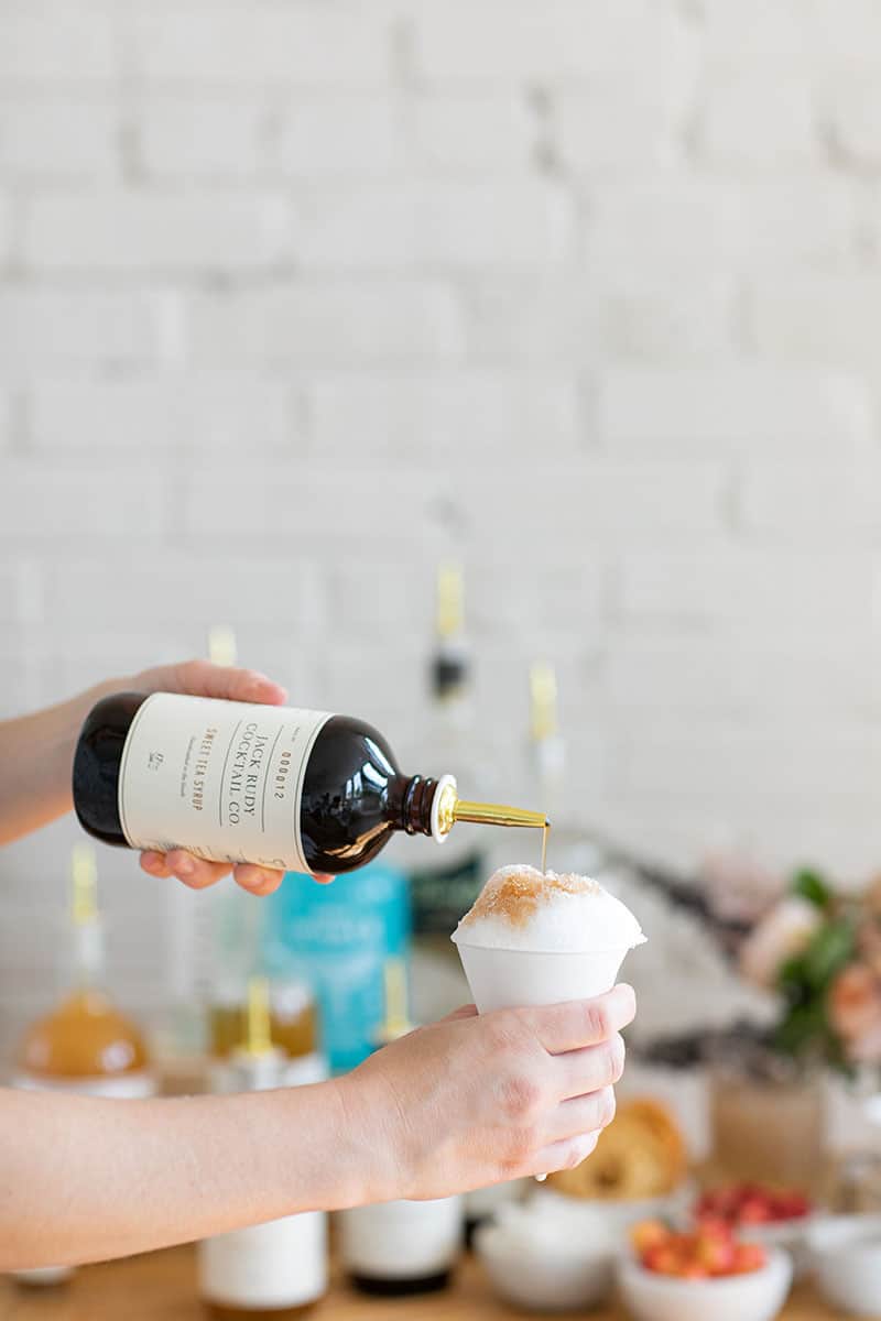 Pouring cocktail syrup over a snow cone. 