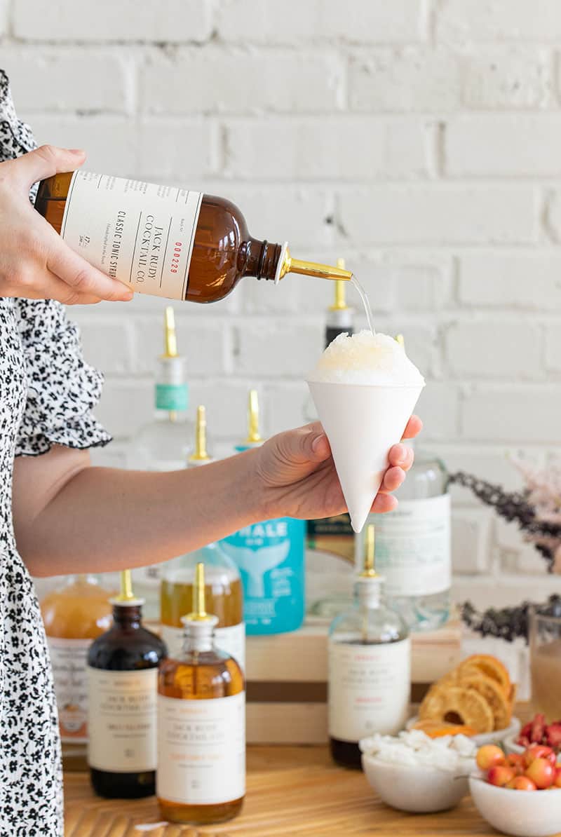 Pouring syrup over ice in a snow cone cup.