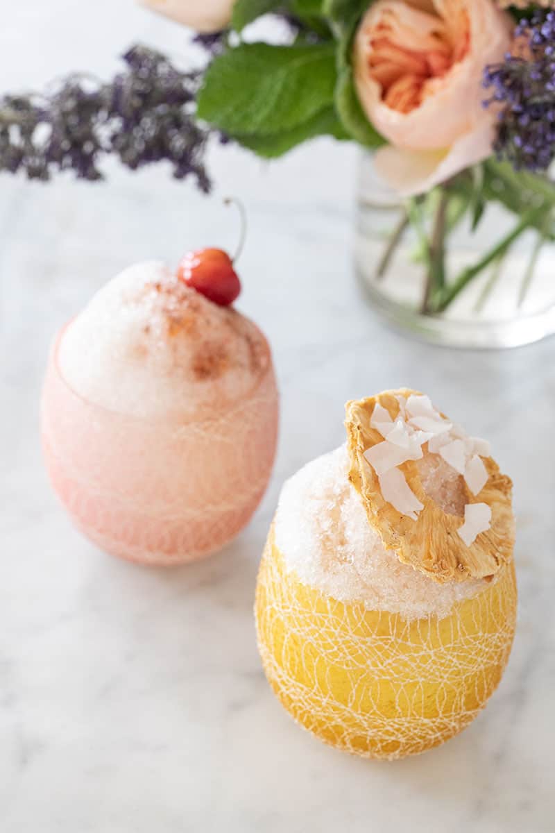 Shaved ice in a cup with cherry and pineapple toppings.