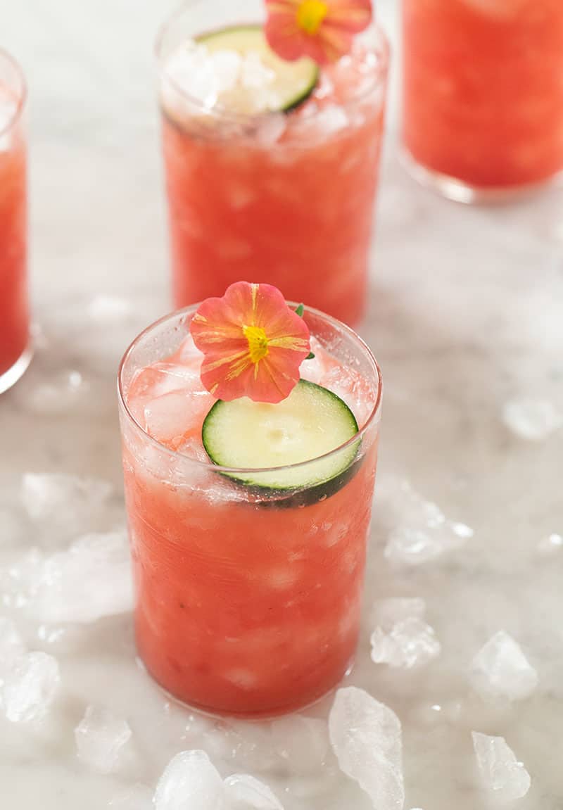 watermelon drink in a glass with cucumber and edible;e flowers.