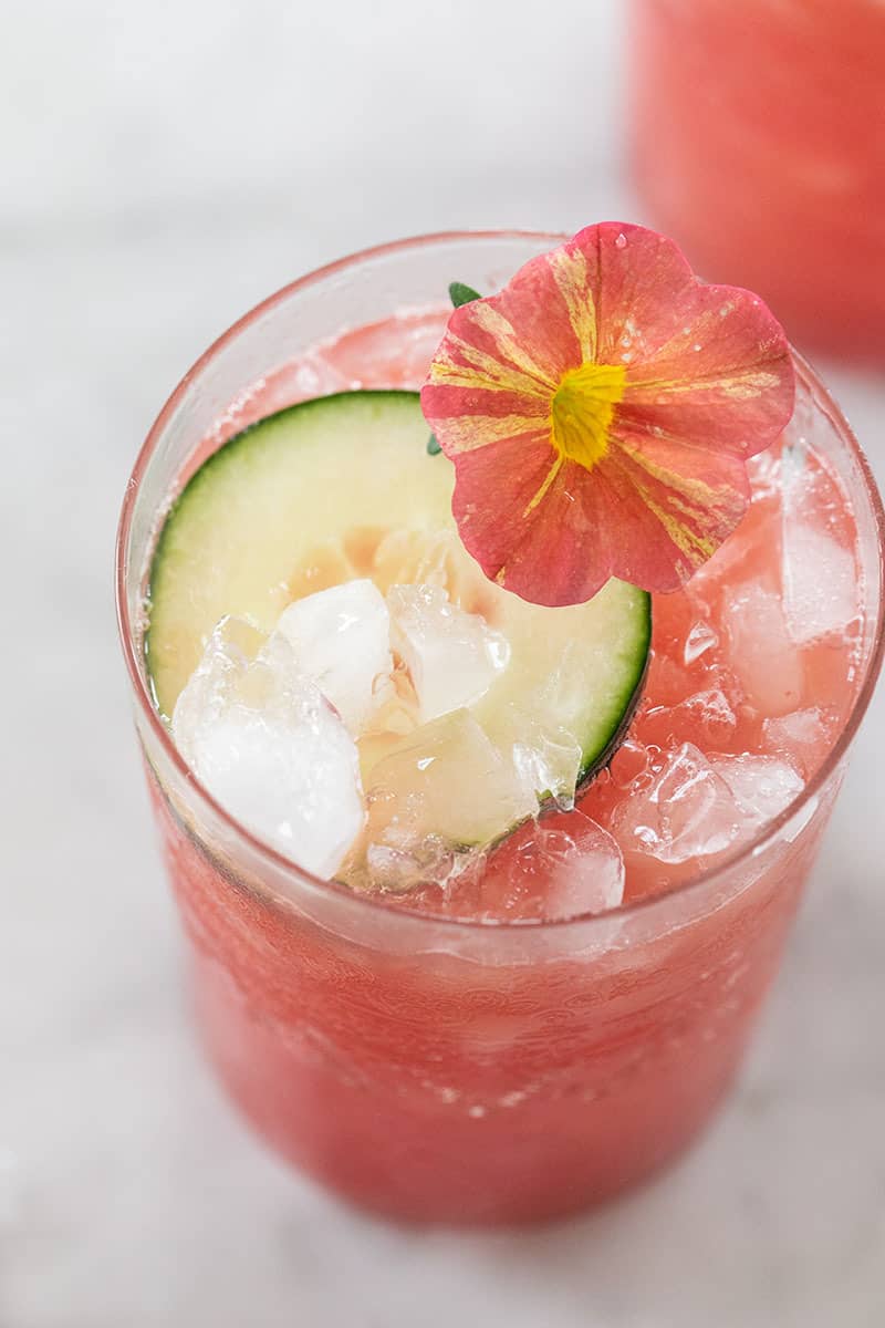 pink watermelon drink with cucumber and edible flowers