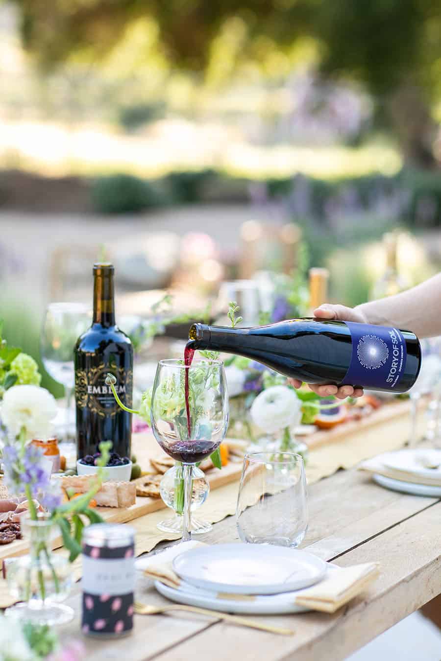 Girl pouring wine in a wine glass for a cheese party.