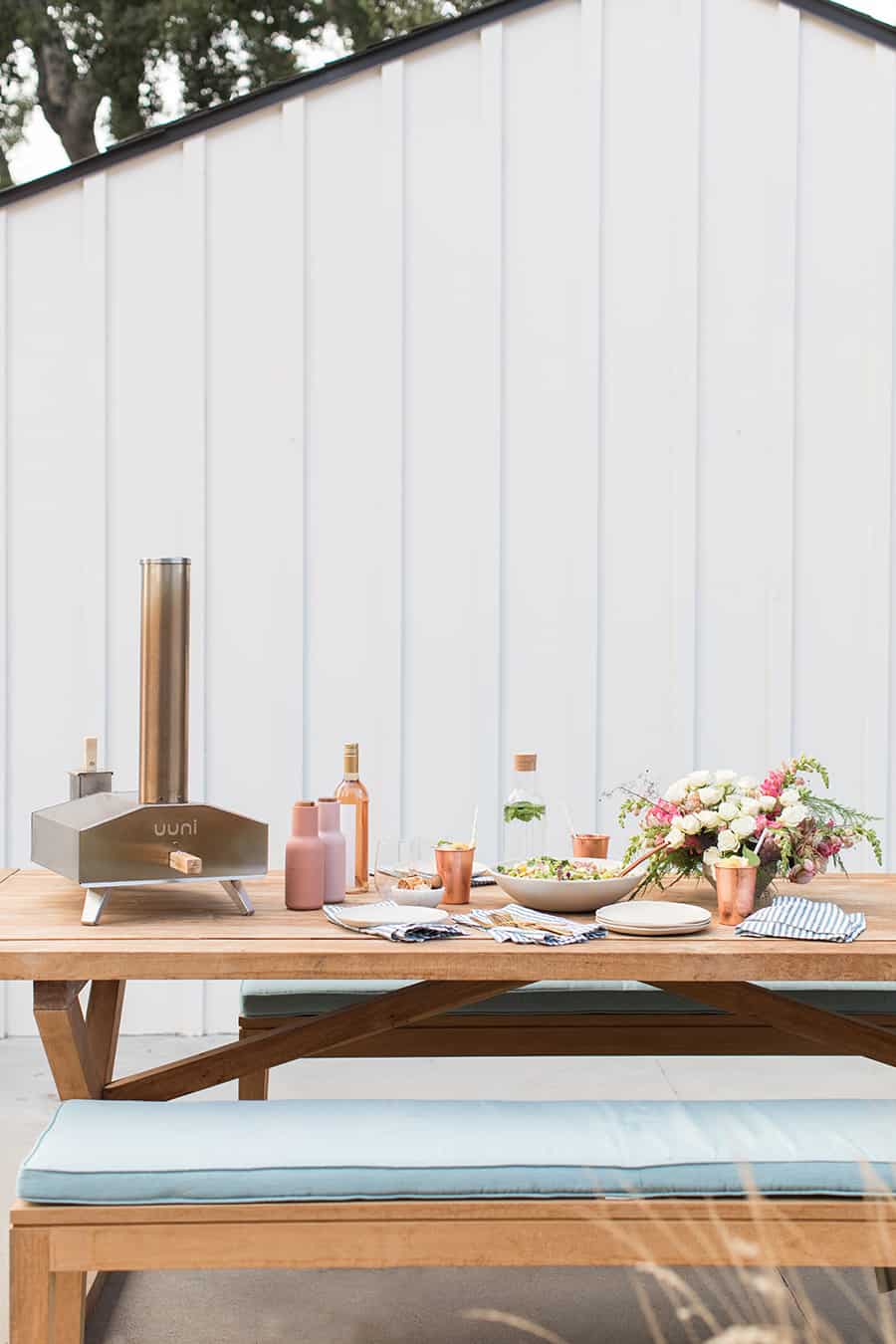 Pizza oven and pizza on a wooden table for dining alfresco.