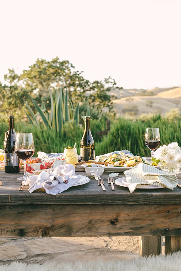 Table setting with golden light and trees and wine bottles