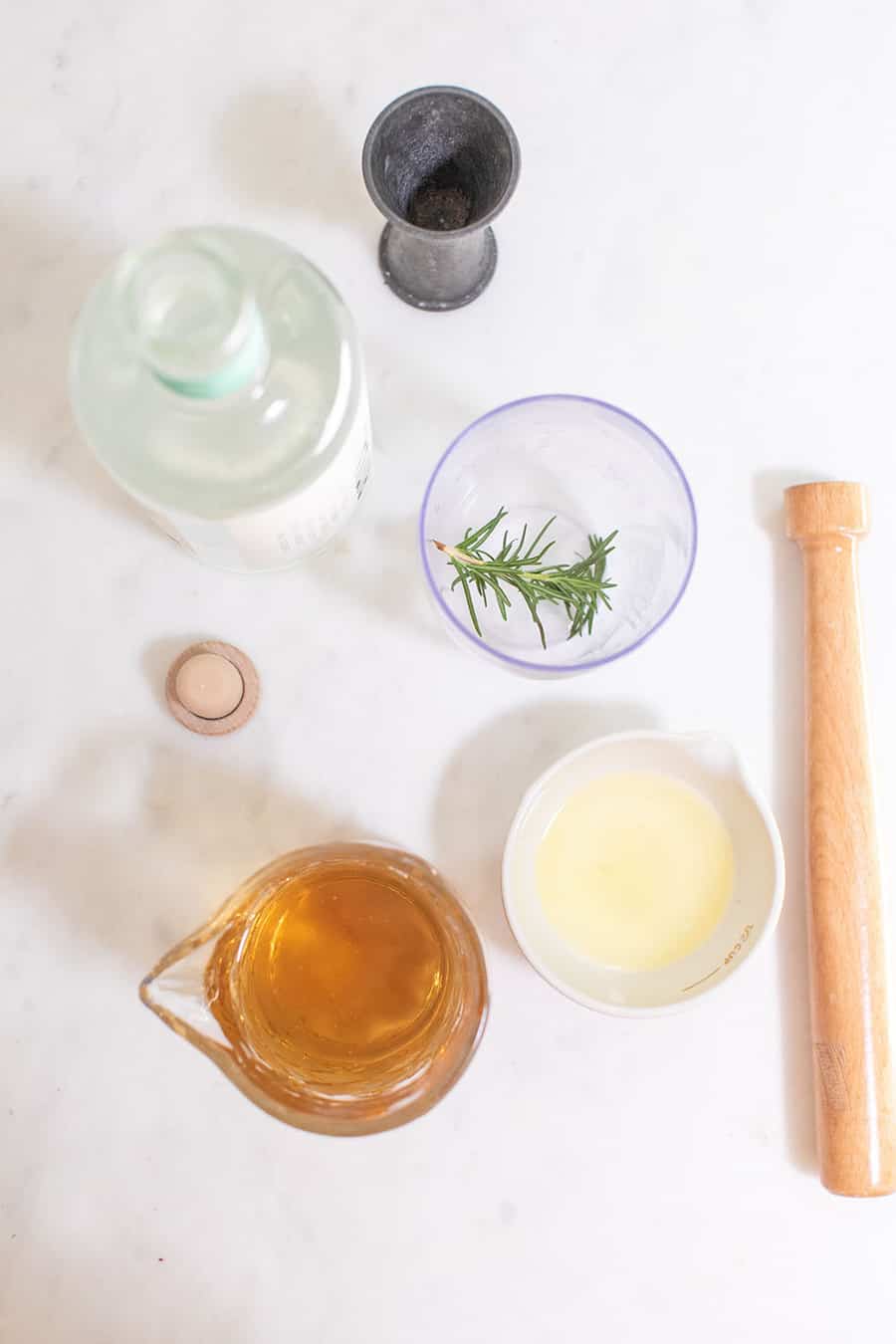 Ingredients to make a mocktail with lemon juice, rosemary, muddler. 