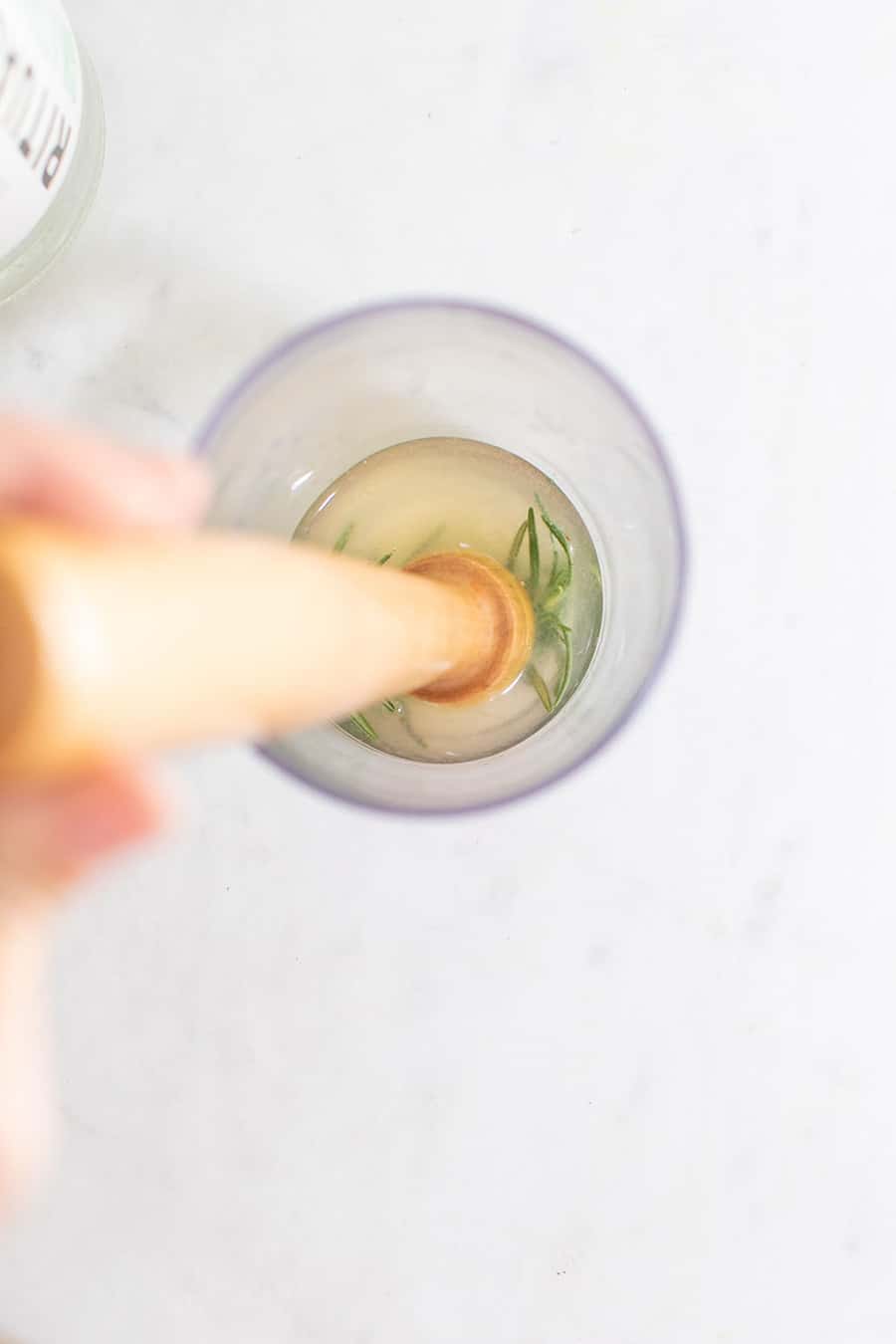 Muddling herbs in a cocktail shaker.