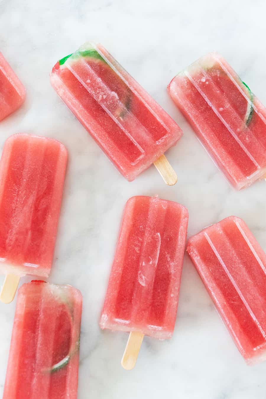 Watermelon popsicles with watermelon candy inside on a marble table. 