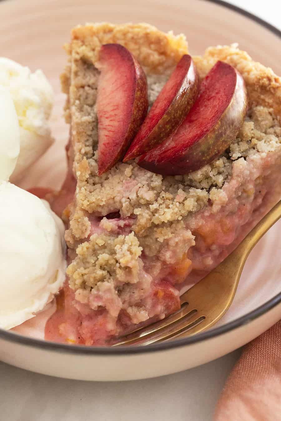 Plumcot and aprium pie with crumble top and sliced plumcots.
