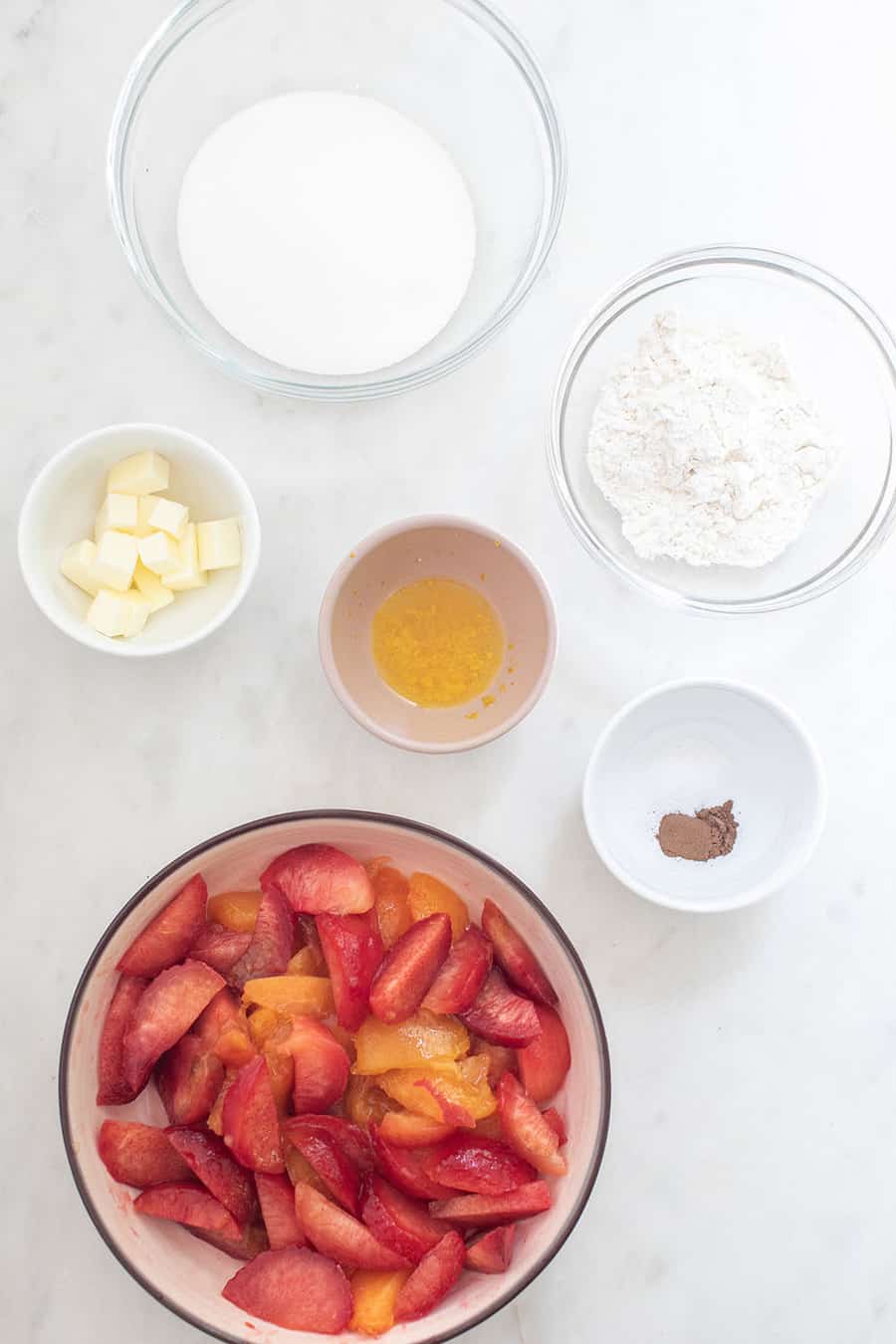 sugar, butter, orange, flour, slices and sliced fruit in a bowl.