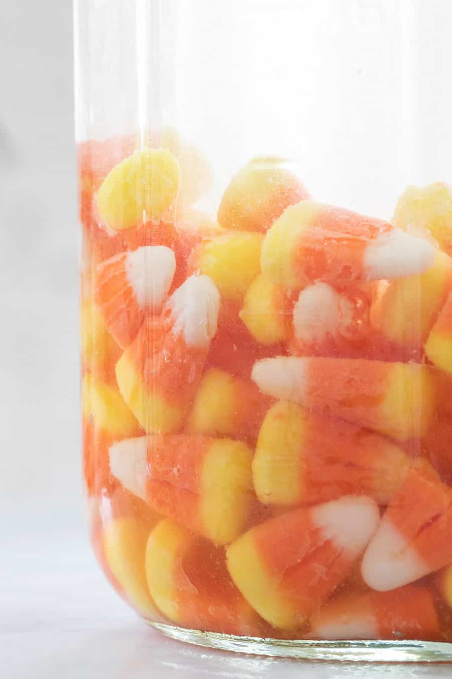 Vodka and candy corn in a glass jar.
