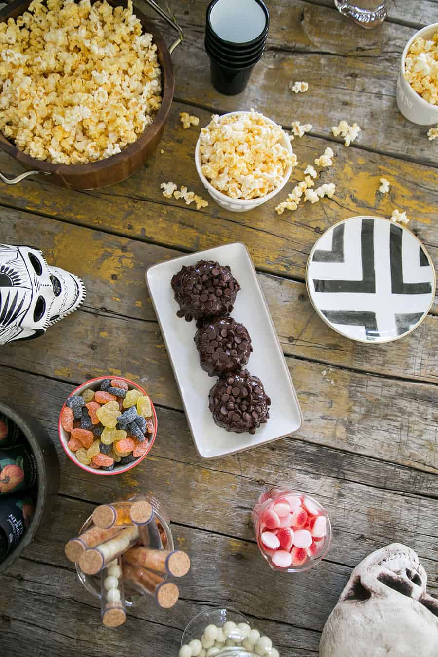 Halloween desserts on a wooden, rustic table with skeleton skulls.