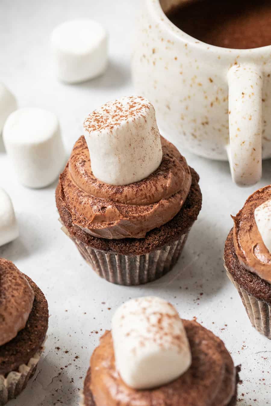 Hot chocolate cupcake with a large marshmallow and sprinkles with hot chocolate.