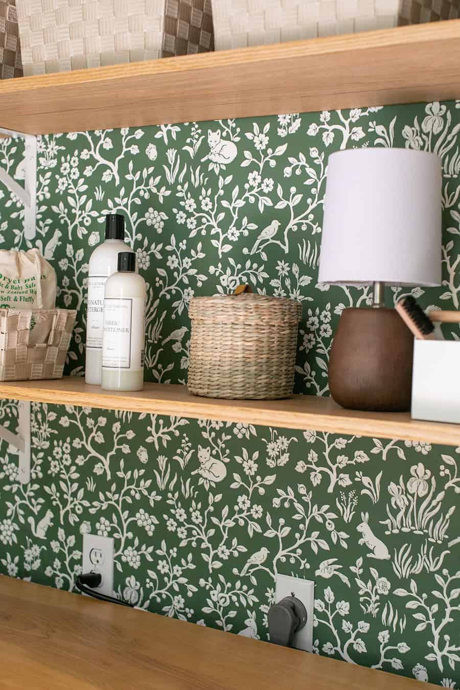 Oak shelving in a laundry closet with soap, lamps and baskets.