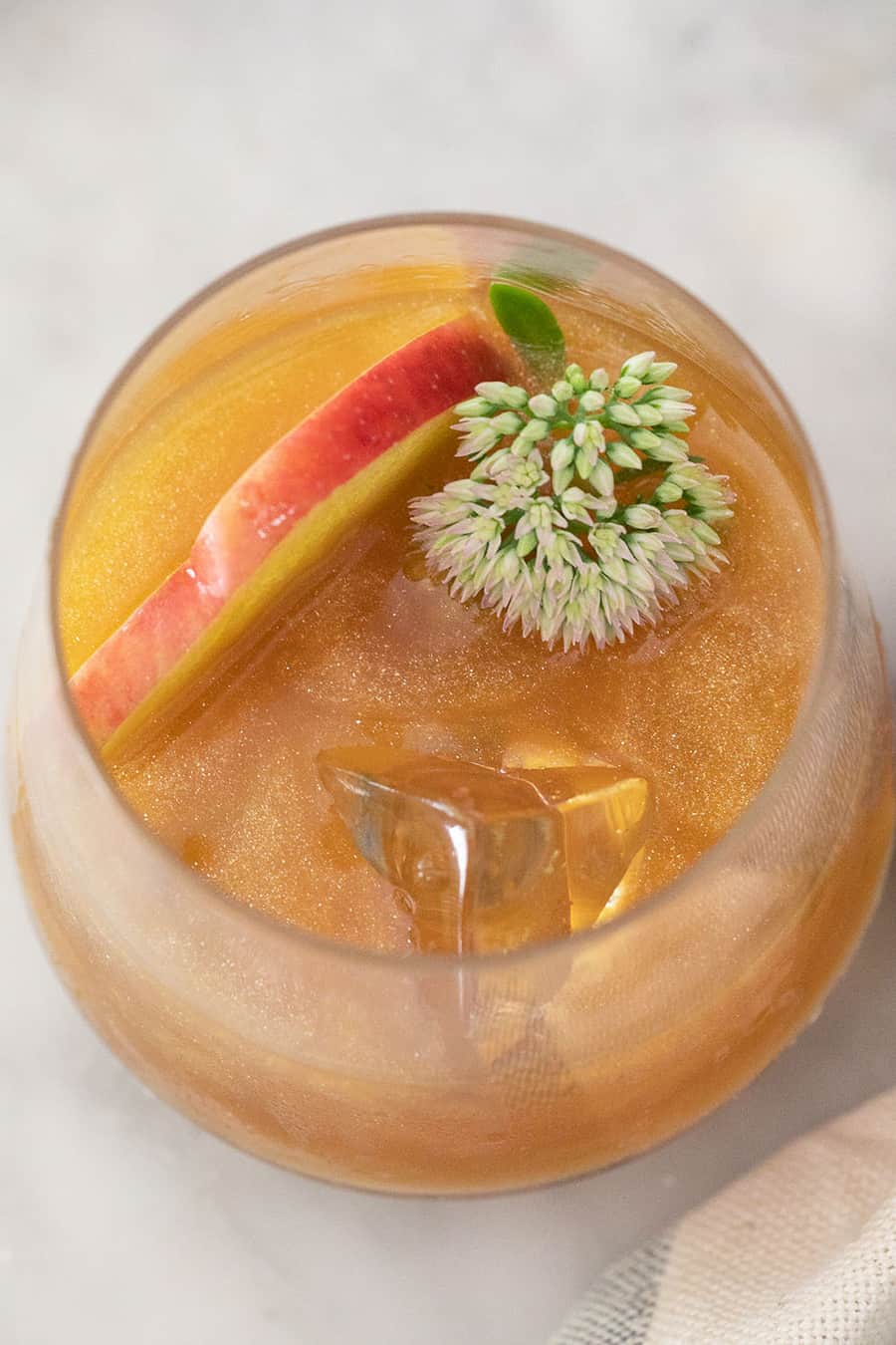 A poison apple cocktail with shimmer, flowers and apple slices - recipe box