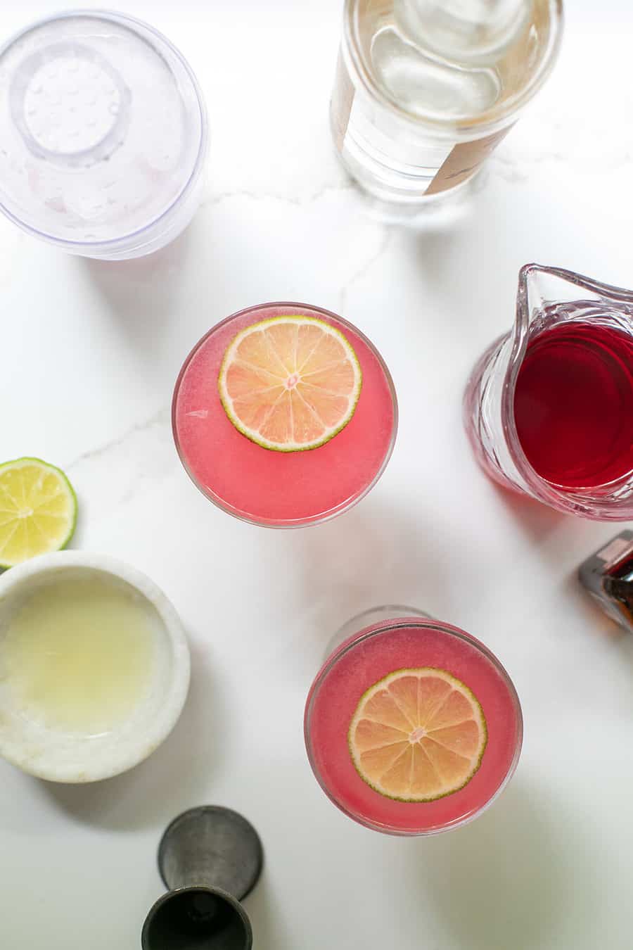 Two cosmopolitan cocktail on a marble table with ingredients. - elegant cocktail, fresh lime