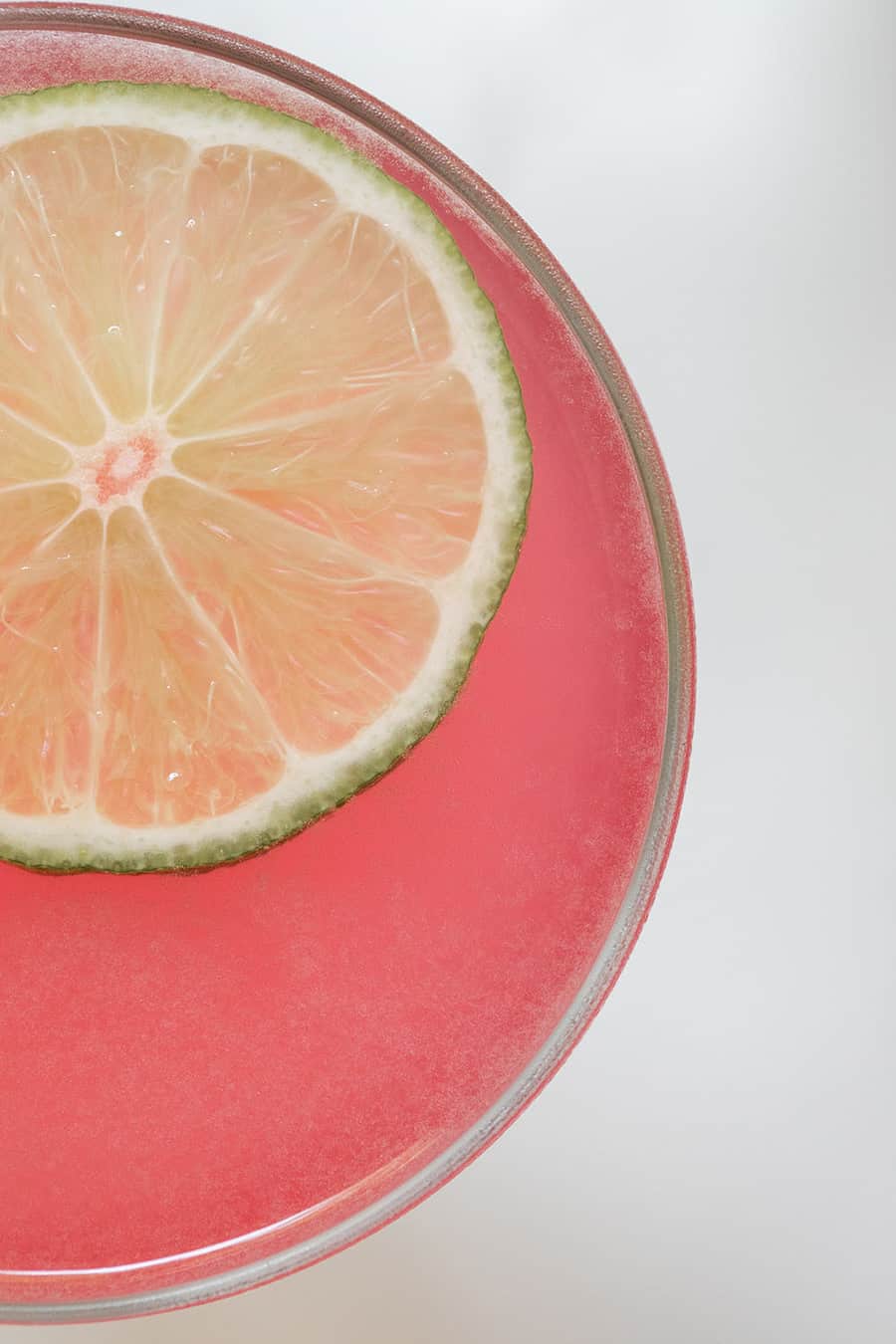 Close up photo of a cosmopolitan cocktail recipe with a lime wheel.