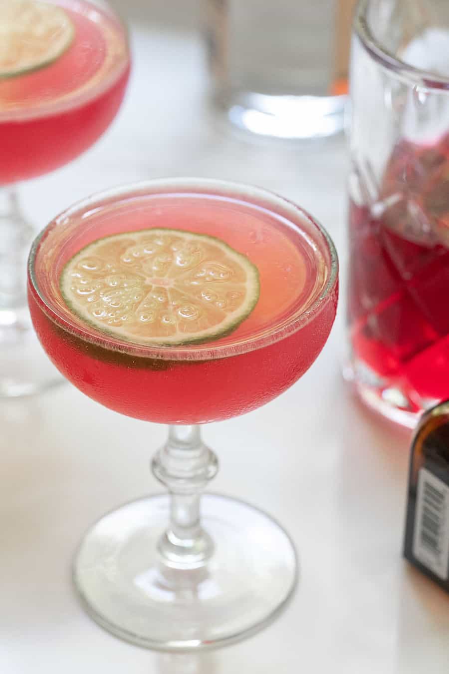 Pink cosmopolitan cocktail recipe with a lime slice.